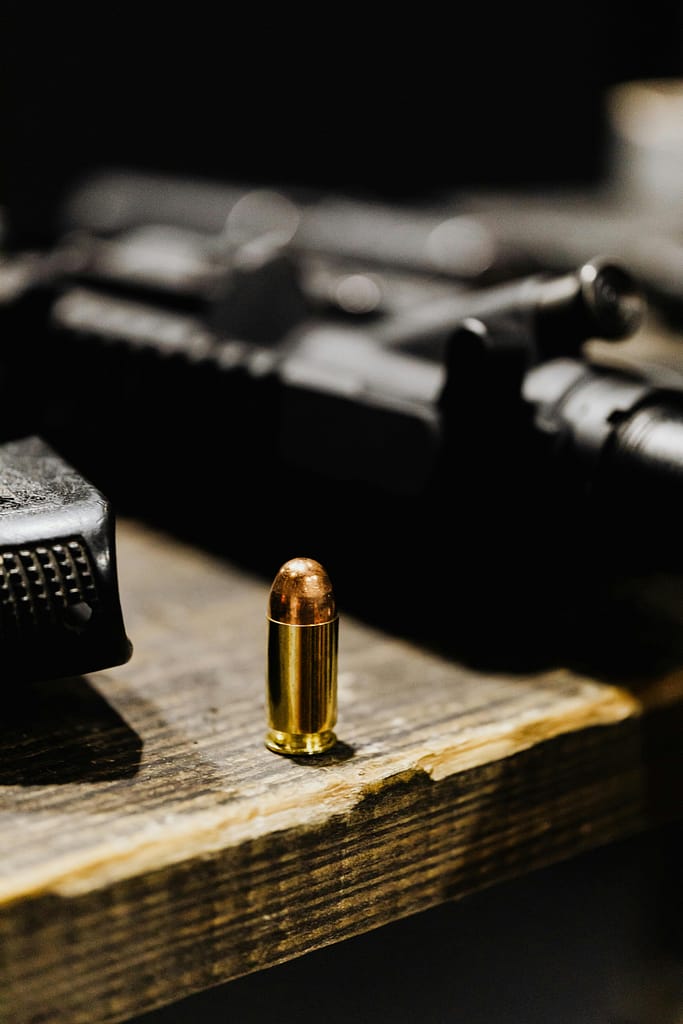 A focused view of a bullet standing upright on a rustic wooden surface.